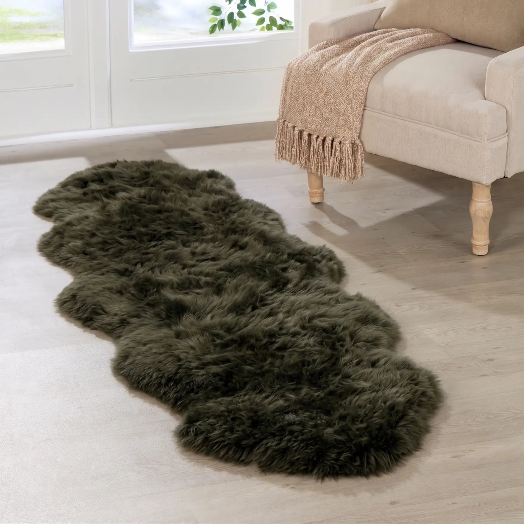 Green sheepskin rug on a light wooden floor in a room with a window view.