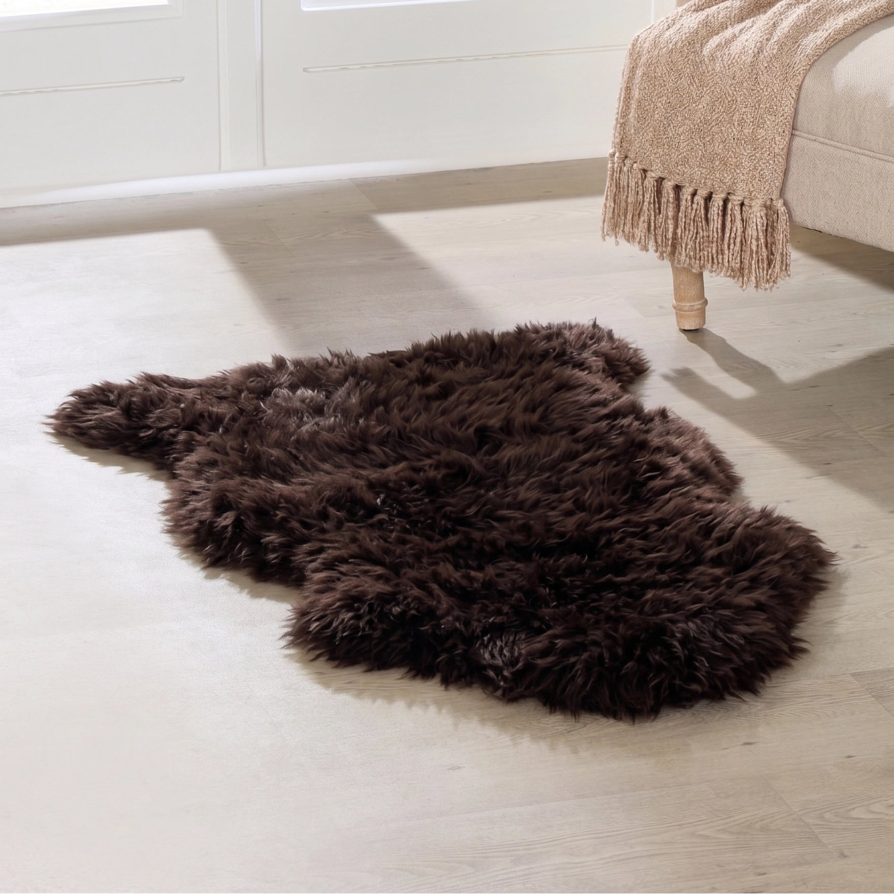 Brown fur rug on a light wooden floor with a window in the background
